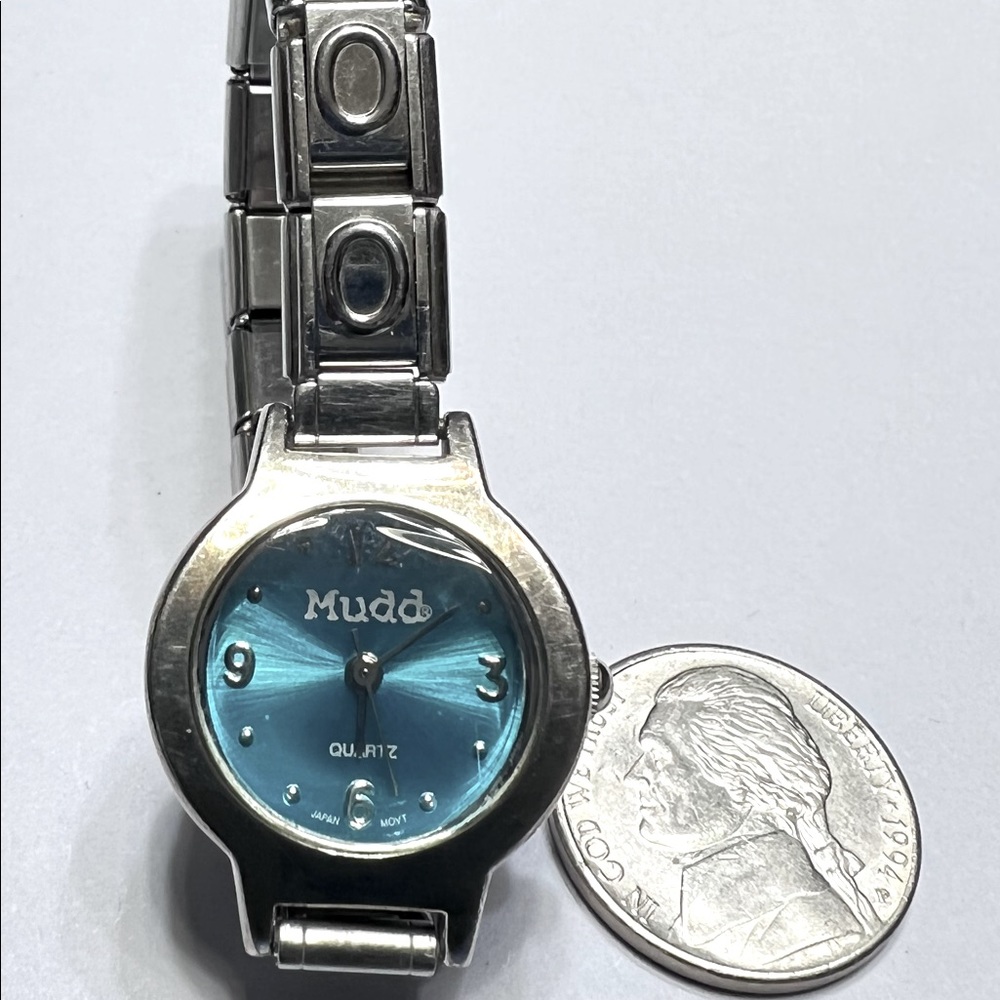 Mudd ladies watch. Blue face with silver elastic band. Works excellent.